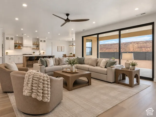 Open-concept kitchen and living area featuring white cabinetry, wood-finish flooring, recessed lighting, a modern ceiling fan, and expansive sliding glass doors with a prominent mountain backdrop