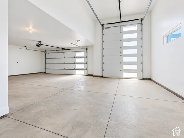 Expansive garage featuring high ceilings, multi-pane glass panel doors, and finished concrete flooring