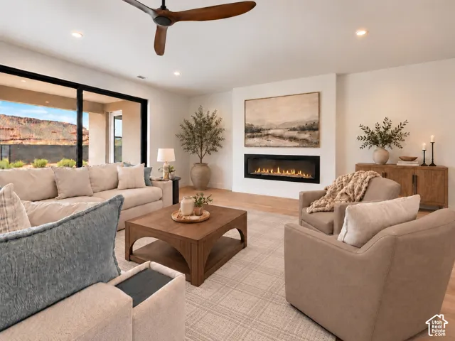 Living area featuring oversized sliding glass doors, wood-finish flooring, and ceiling fan. Home is virtually staged and represents a fireplace not currently installed. Can customize fireplace and wall based on Builders Design center, upon contract negoti