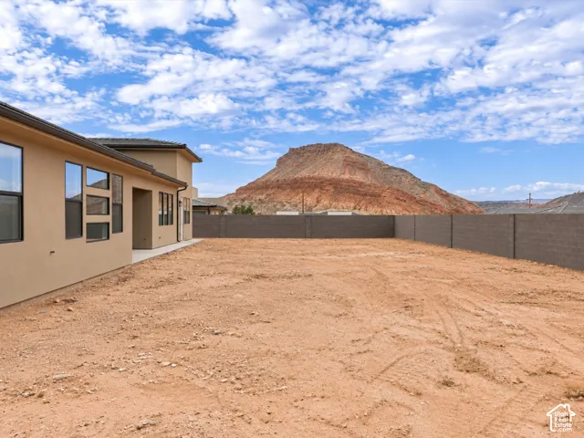 Expansive backyard featuring a concrete block perimeter wall, stucco exterior finish, and mountain scenery