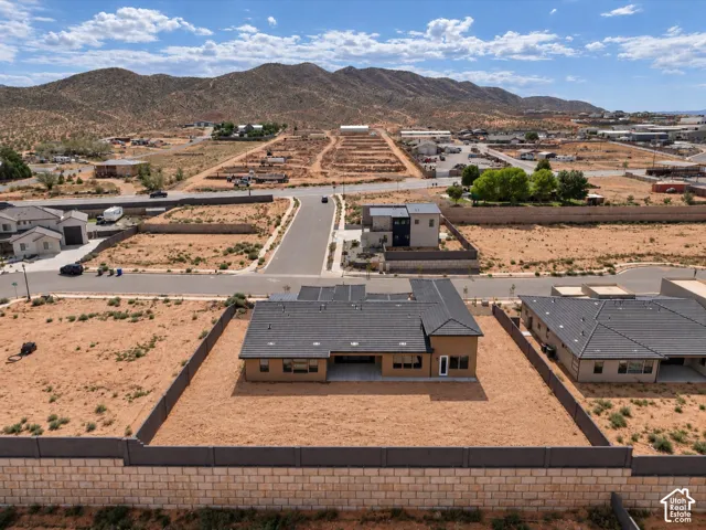 Single-story residence featuring a tile roof, covered rear patio, and expansive desert terrain enclosed by masonry perimeter walls