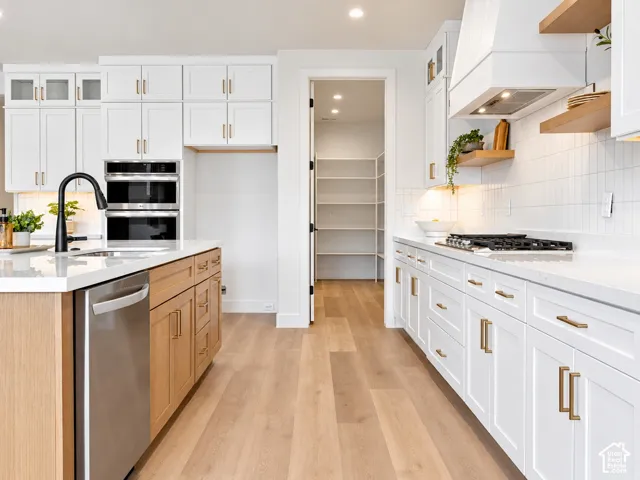 Kitchen featuring white shaker cabinetry, wood-finish island base, quartz countertops, built-in oven, and walk-in pantry