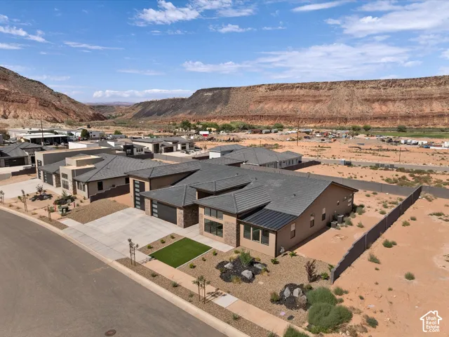 Single-story residence featuring a multi-gabled tile roof, stone masonry accents, a three-car garage, and desert-inspired xeriscaped grounds