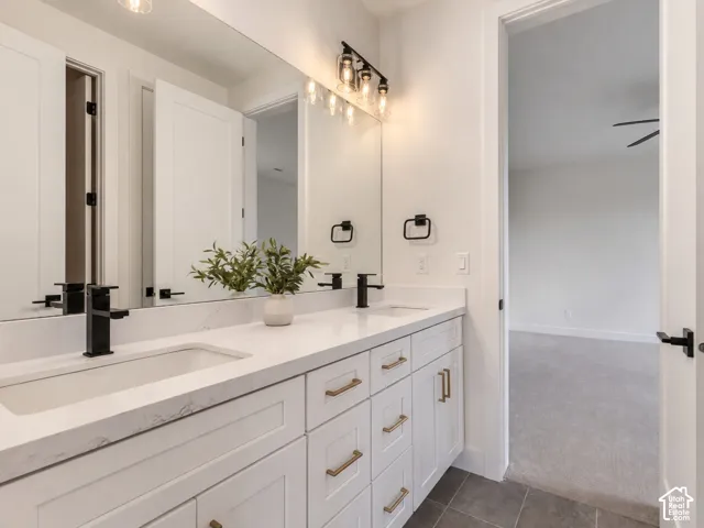 Jack-Jill bathroom, not staged. Double vanity featuring white shaker-style cabinetry, white quartz countertops with dual integrated sinks, and a full-width mirror
