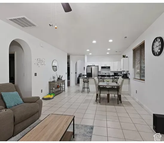 Open-concept living space featuring neutral tile flooring, recessed ceiling lighting, arched wall openings, and white cabinetry