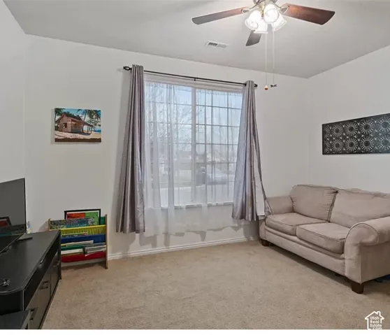 Carpeted interior room featuring a multi-pane grid window and a ceiling-mounted light fixture with a fan