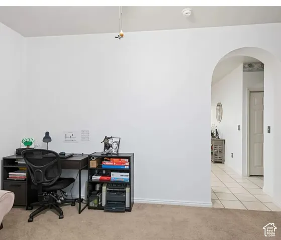 Interior space featuring arched entryway, neutral wall color, and tile flooring