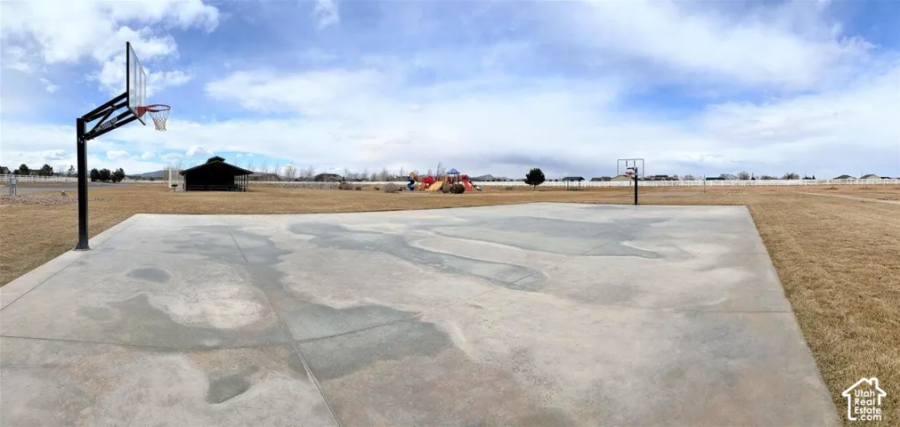 Concrete sports court featuring dual built-in basketball hoops, expansive grounds, and permanent recreational structures