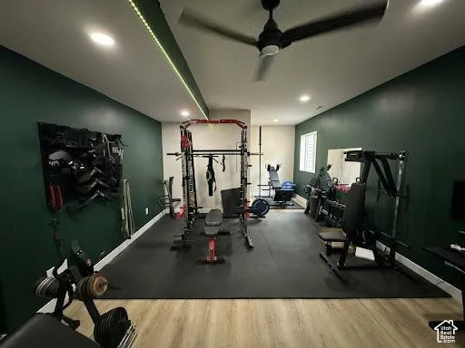 Interior space featuring wood-finish flooring, dark green accent walls, recessed ceiling lighting, a ceiling fan, and integrated linear LED strip lighting