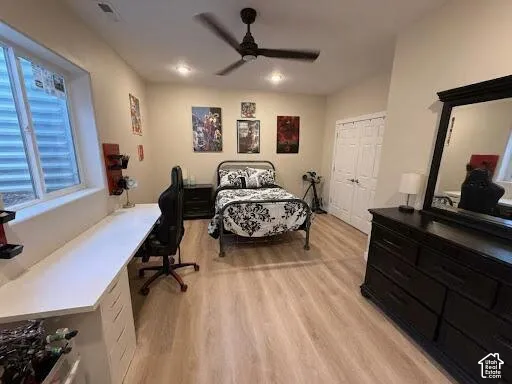 Wood-finish flooring, matte black ceiling fan, recessed lighting, double-door closet, and built-in desk cabinetry