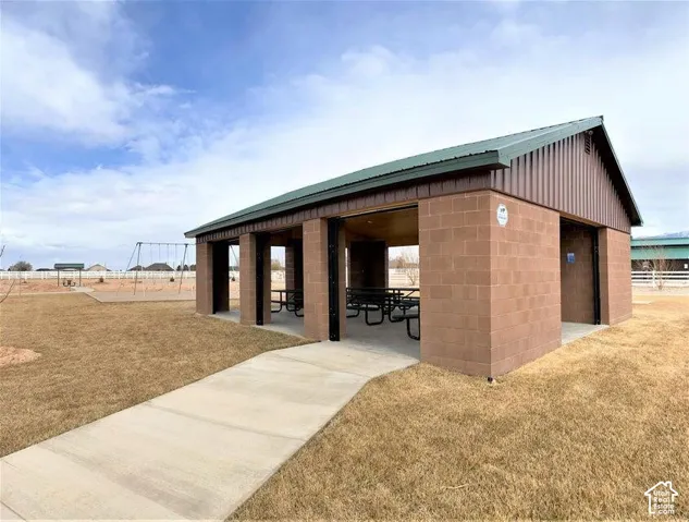 Covered pavilion featuring masonry construction, a metal roof, concrete walkway, and open-air design