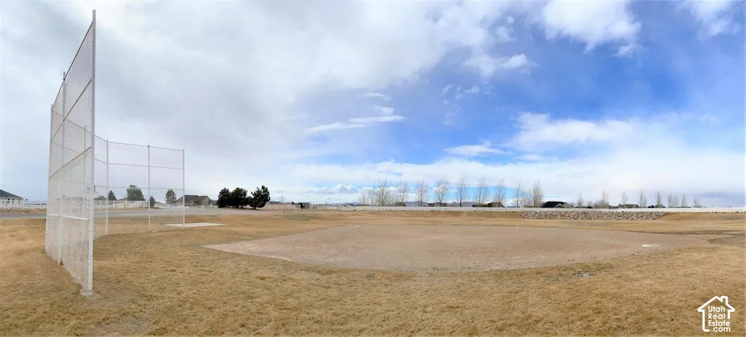 Expansive open-air lot featuring a baseball infield diamond, dirt playing surface, and perimeter backstop fencing