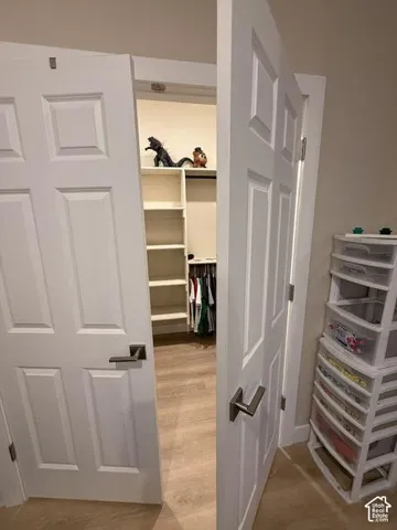 Double-door closet featuring custom built-in shelving, integrated hanging rods, and wood-finish flooring