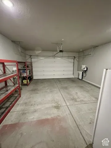 Garage interior featuring a concrete floor, finished walls, and a dedicated electric vehicle charging station