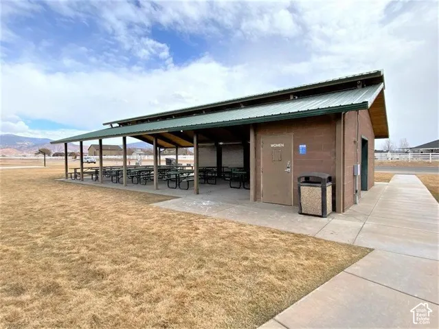 Open-air pavilion featuring a metal roof, concrete slab flooring, integrated lighting, masonry construction, and surrounding concrete walkways