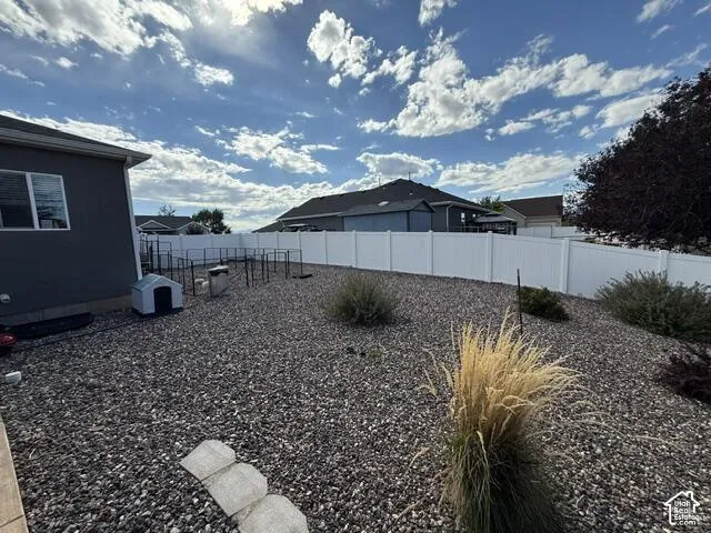 Backyard featuring a white vinyl privacy fence, rock landscaping, and low-maintenance ornamental grasses