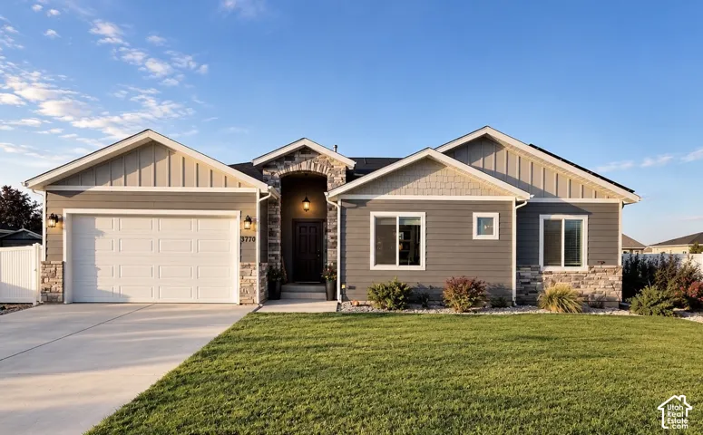 Single-story residence featuring horizontal lap and vertical board-and-batten siding, stone veneer accents, an arched stone-clad entryway, and a concrete driveway