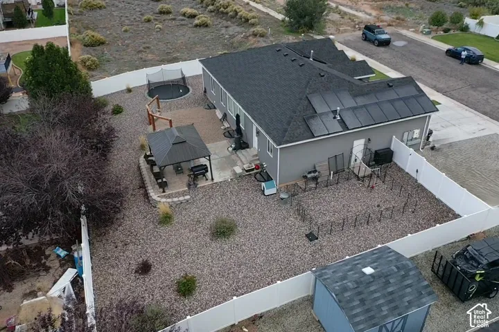 Exterior features include solar panel arrays, a fenced backyard, a concrete patio, a metal-roof gazebo, and a detached storage structure