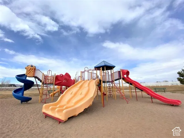 Outdoor recreation area featuring a multi-level playground structure, dual slides, a spiral slide, and sand surfacing