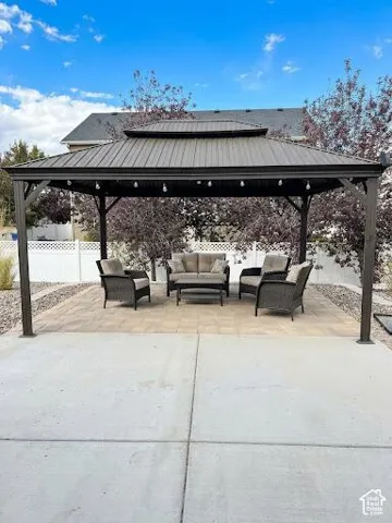 Permanent metal-roofed gazebo featuring a steel frame, set upon a paved stone patio with an expansive concrete base and perimeter white fencing