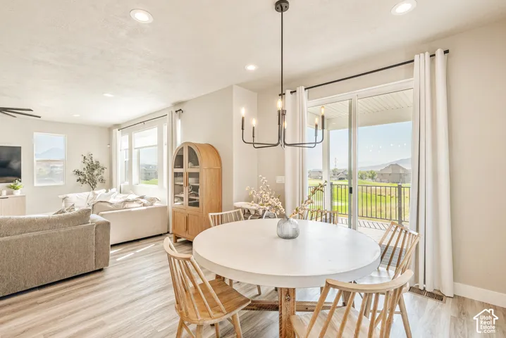 Open-concept area featuring wood-finish flooring, recessed lighting, a modern iron chandelier, and a sliding glass door