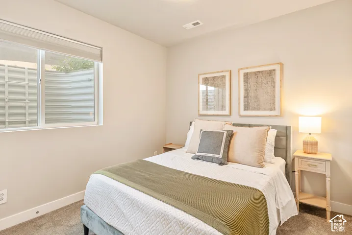 Neutral-toned interior featuring wall-to-wall carpeting and a wide sliding window with an integrated egress well