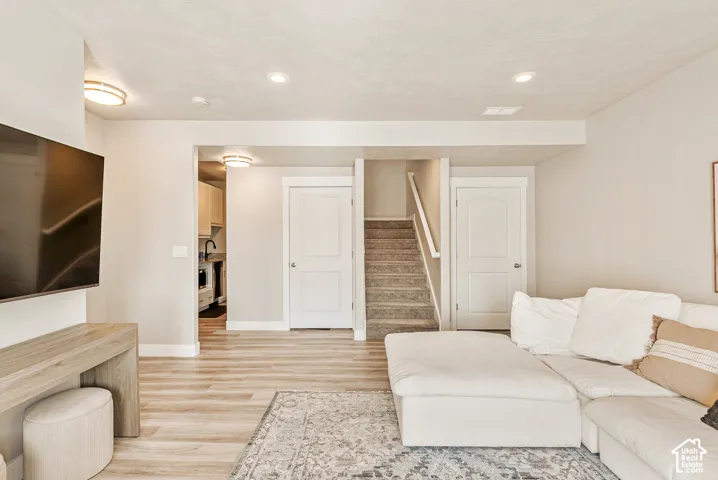 Neutral interior featuring wood-finish flooring, recessed lighting, white interior doors, and carpeted staircase with white handrail