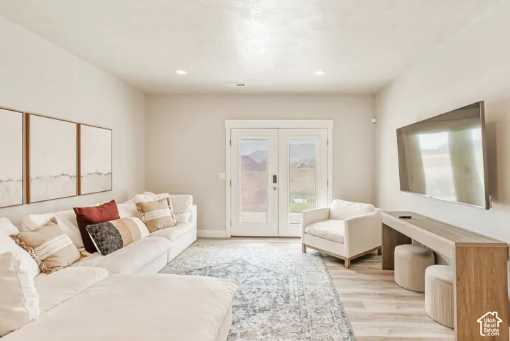 Neutral-toned interior space featuring wood-finish flooring, recessed lighting, and double-paned glass entry doors with mountain-range scenery