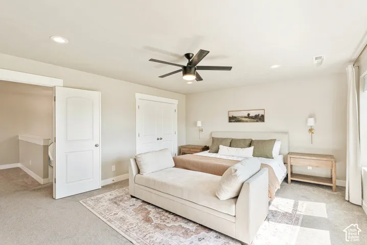 Neutral-toned bedroom featuring recessed lighting, a multi-blade ceiling fan, wall-mounted light fixtures, and double-door closet cabinetry