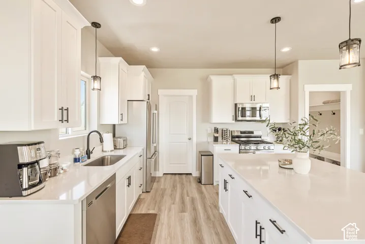 Kitchen featuring white cabinetry, quartz countertops, central island, stainless steel appliances, and wood-finish flooring