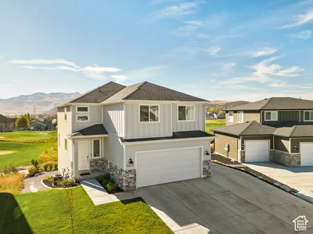 Modern two-story residence featuring a clean contemporary exterior with mixed material cladding in cream and charcoal tones, complemented by a dark asphalt shingle roof