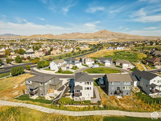 Aerial perspective of residential properties featuring multi-level construction, attached covered decks, concrete paved walkways, and direct access to open terrain with mountain backdrop