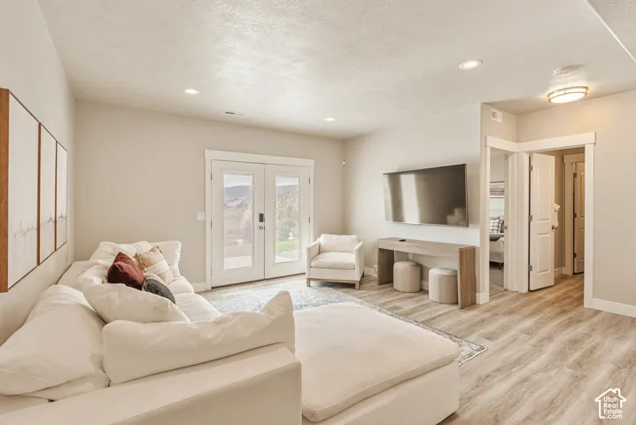Neutral-toned living space featuring wood-finish flooring, recessed lighting, and double glass-panel doors