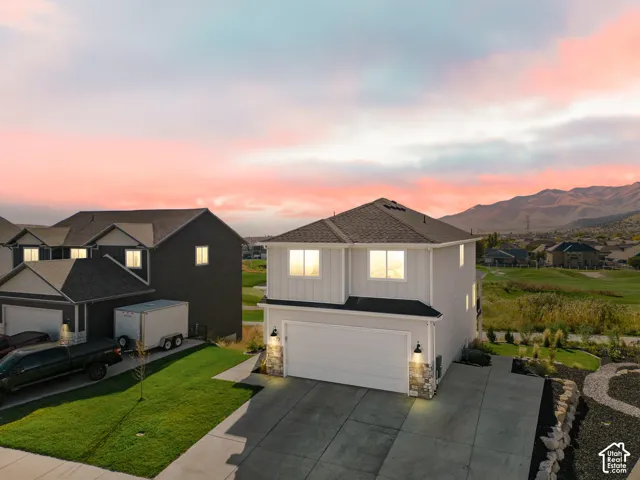 Two-story exterior featuring vertical siding, stone masonry accents, a paved driveway, and mountain scenery