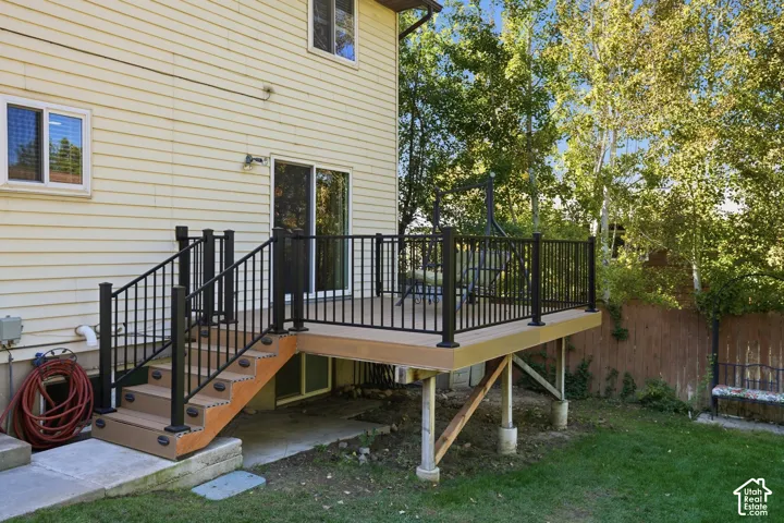 Elevated deck featuring composite decking, black metal railings, integrated stair lighting, and sliding glass door access
