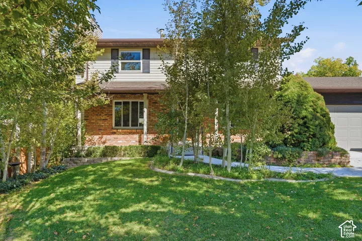 Multi-level exterior featuring a brick and siding facade, concrete walkway, and mature landscaping