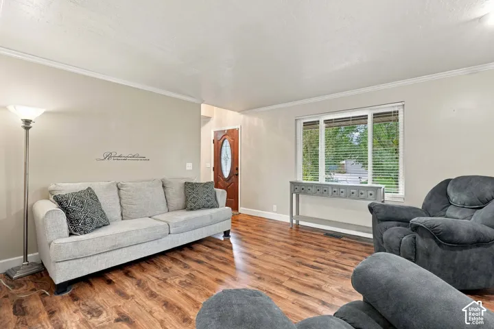 Neutral wall palette, wood-finish flooring, multi-pane window with white trim, and a wood-finish front door with an oval glass insert