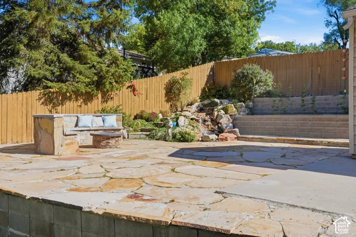 Flagstone patio featuring a built-in stone bench, a circular fire pit, a tiered retaining wall, and a rock water feature
