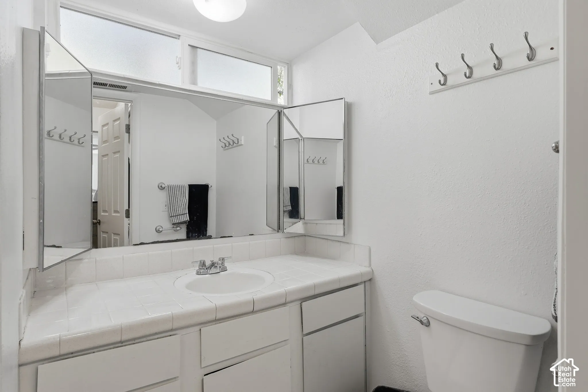 White tiled countertop with an integrated sink and chrome faucet