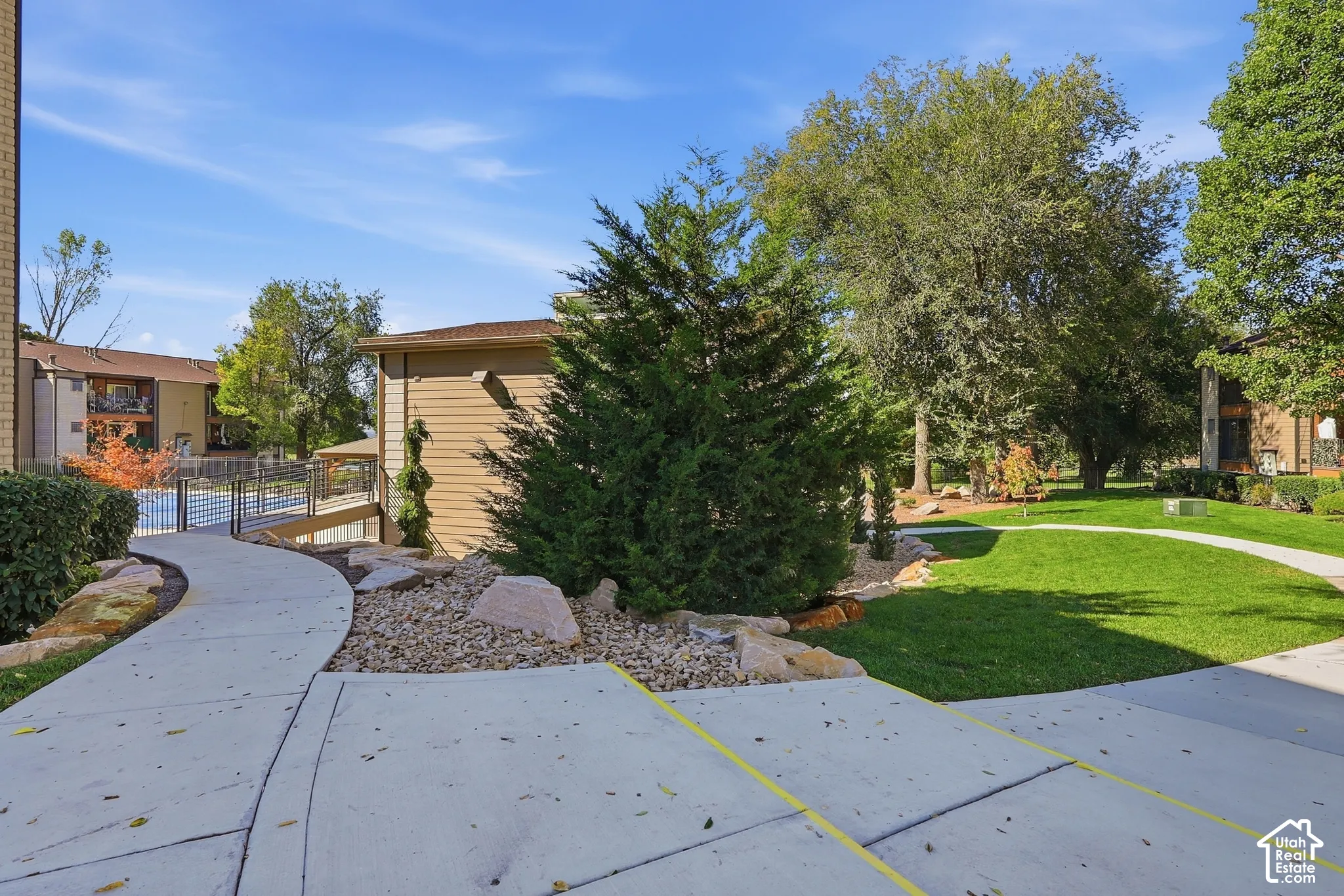 Landscaped grounds featuring a paved walkway, manicured lawn, and mature trees