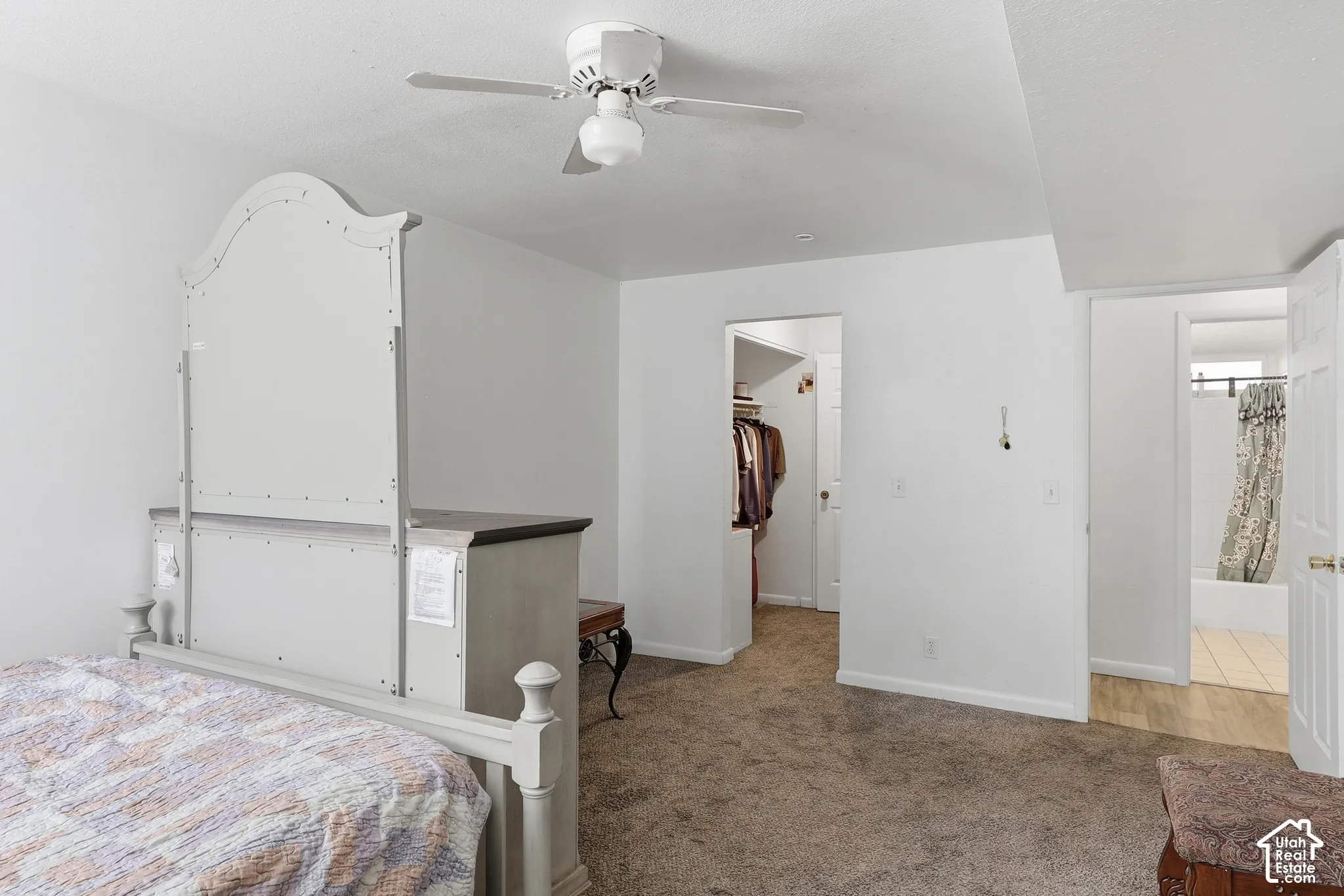 Carpeted flooring, ceiling fan with integrated lighting, white walls, and two open doorways