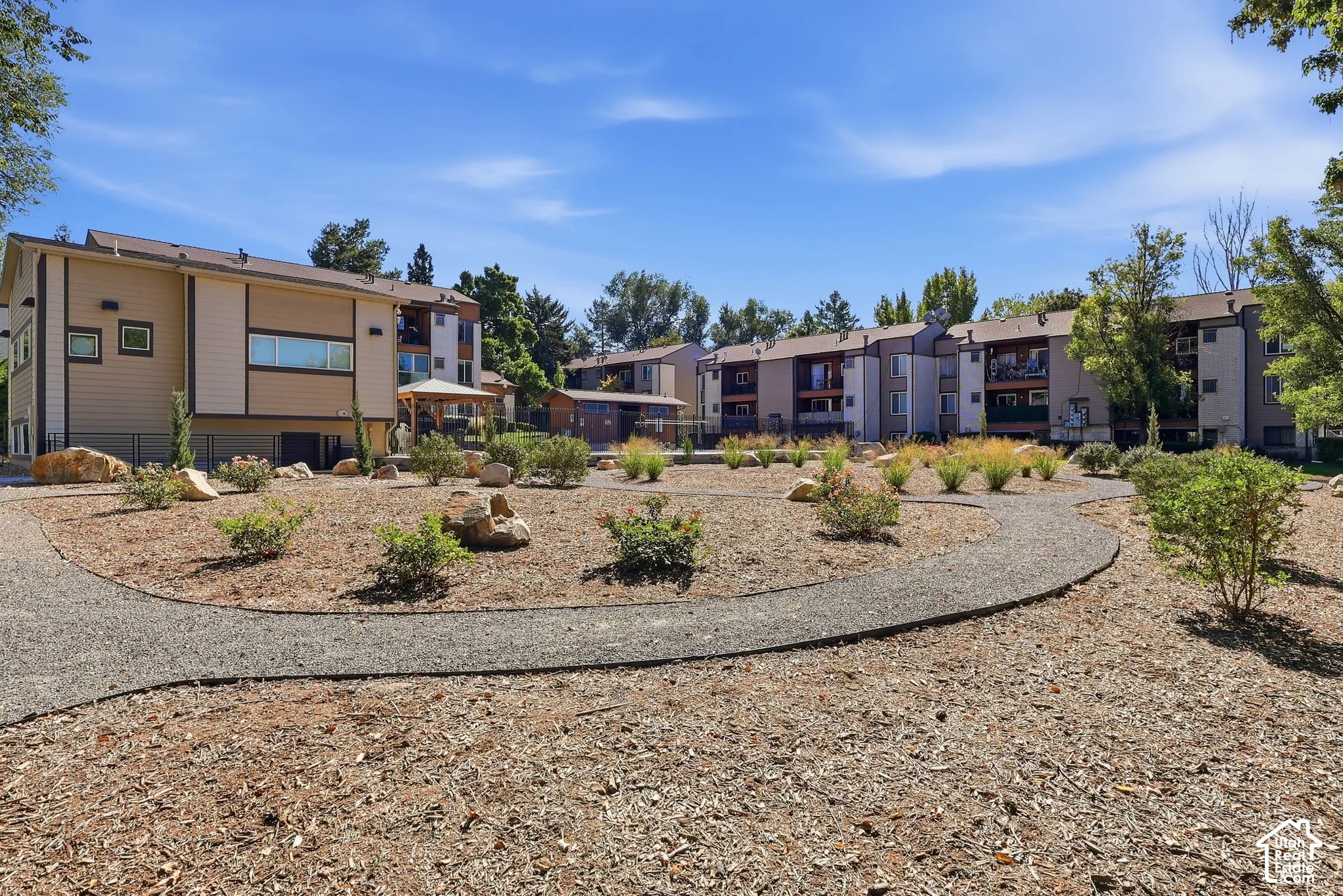 Landscaped grounds with established plantings, decorative rocks, and a winding gravel pathway