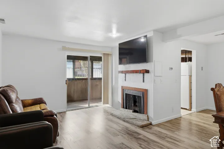 Living area with wood-finish flooring, a fireplace featuring a rustic wood mantel, and sliding glass doors