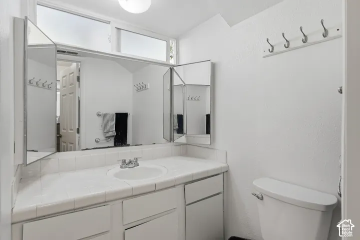 White tiled countertop with an integrated sink and chrome faucet