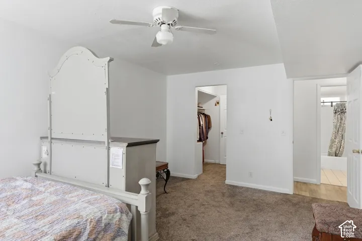 Carpeted flooring, ceiling fan with integrated lighting, white walls, and two open doorways