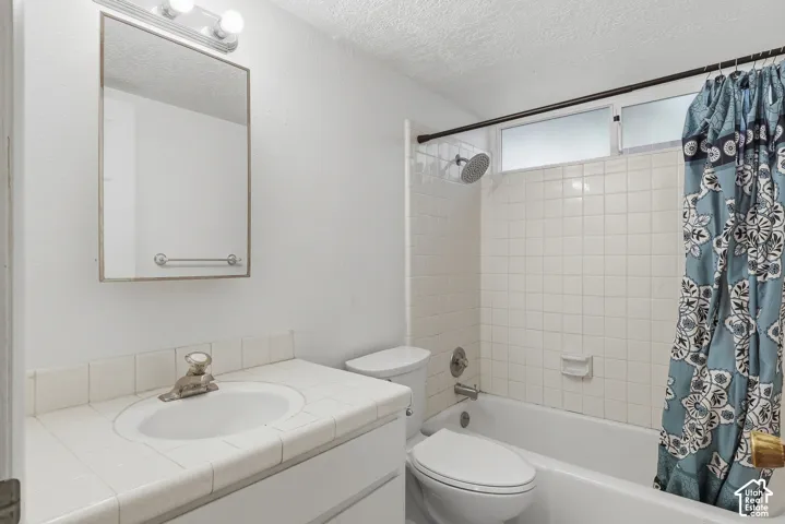 White tiled vanity with integrated sink, wall-mounted medicine cabinet with mirror, and a white tiled shower surround with a bathtub