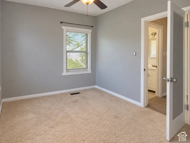 Neutral wall finishes, carpet flooring, ceiling fan with integrated lighting, and window with blinds
