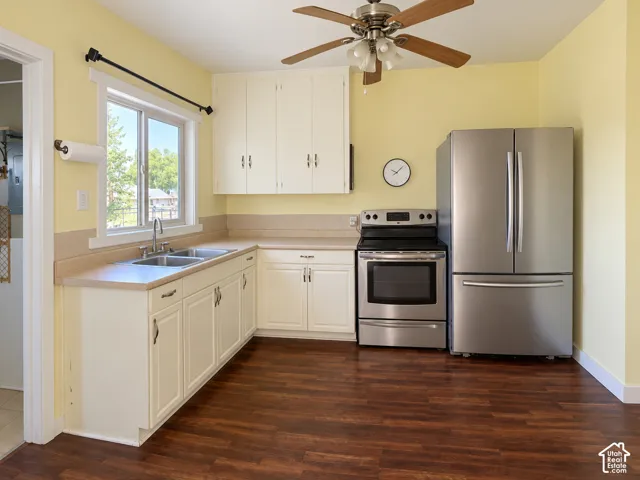 Kitchen featuring wood-finish flooring, white cabinetry, a stainless steel refrigerator, a stainless steel range, and a ceiling fan