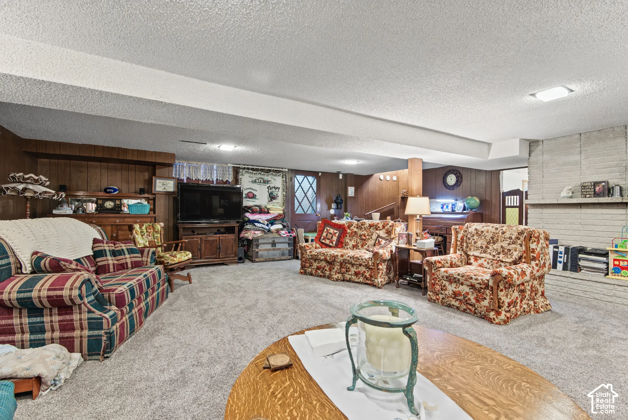 Carpeted lower level featuring a stone-clad fireplace and wood paneling