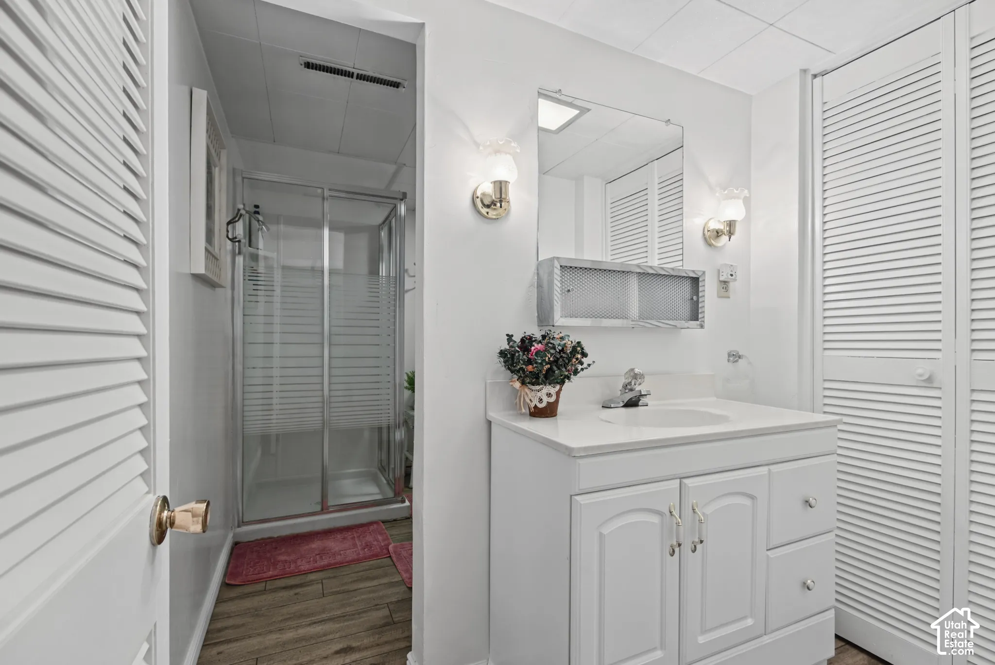 White vanity with integrated sink, mounted mirror, and wall sconces